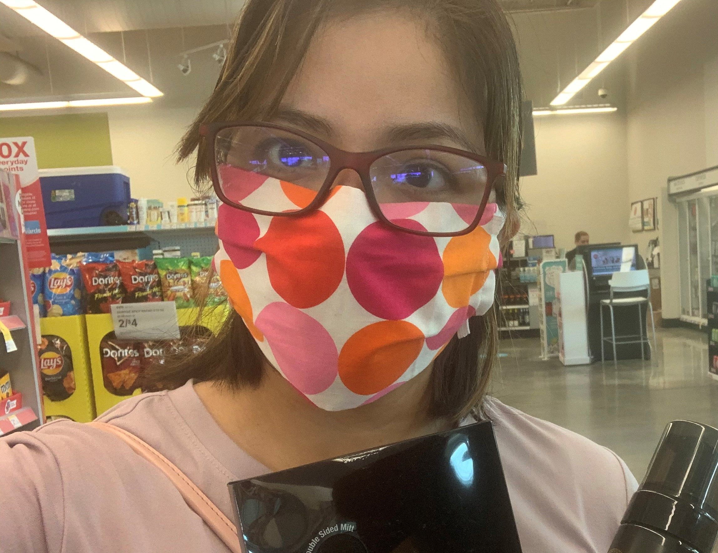 Selfie of a woman with glasses and a mask in a store.